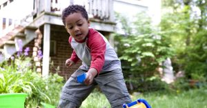 A young African American boy plays in his yard.