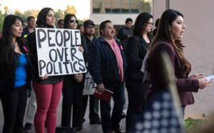 A group of people at an immigrant rights event. One holds a sign that says "People over Politics."