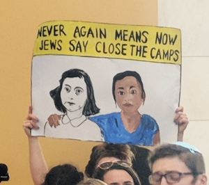 A poster saying "Never Again Means Now. Jews Say Close the Camps."